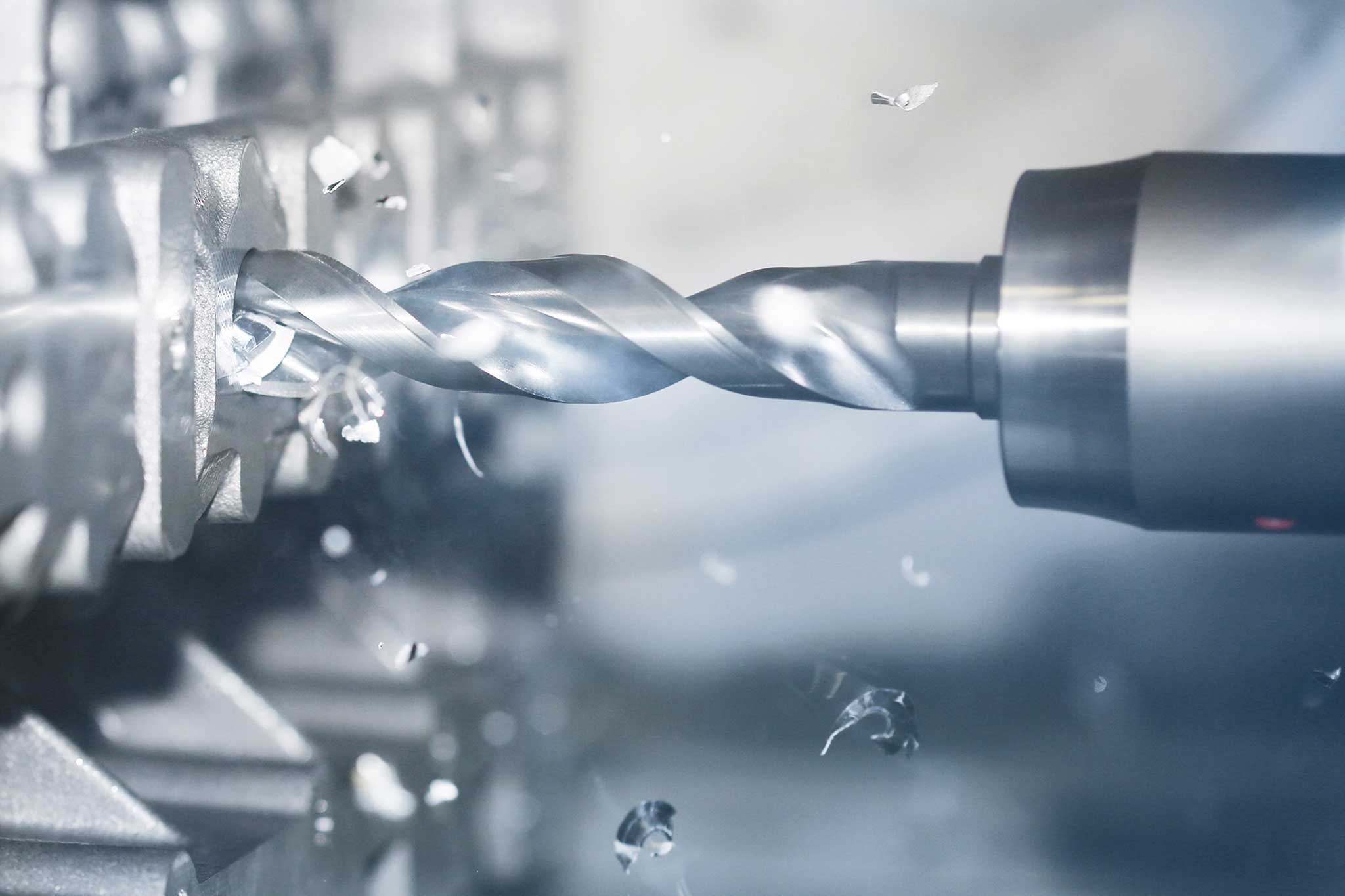 A drill during the machining of a workpiece. There are flying chips.