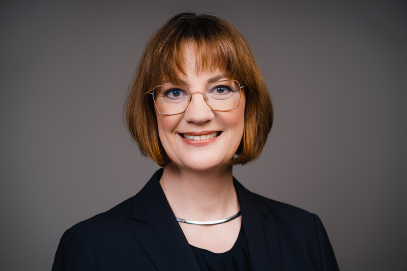 A portrait photo of Dr Karin Jenuwein. She has dark blonde medium length hair and is wearing glasses.