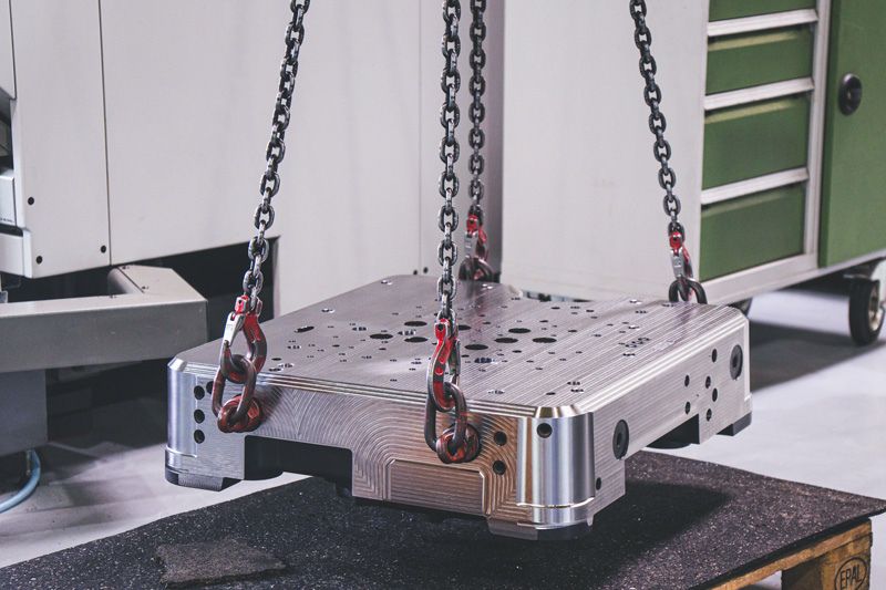 Auf dem Bild wird ein Bauteil auf einer Europalette platziert. 