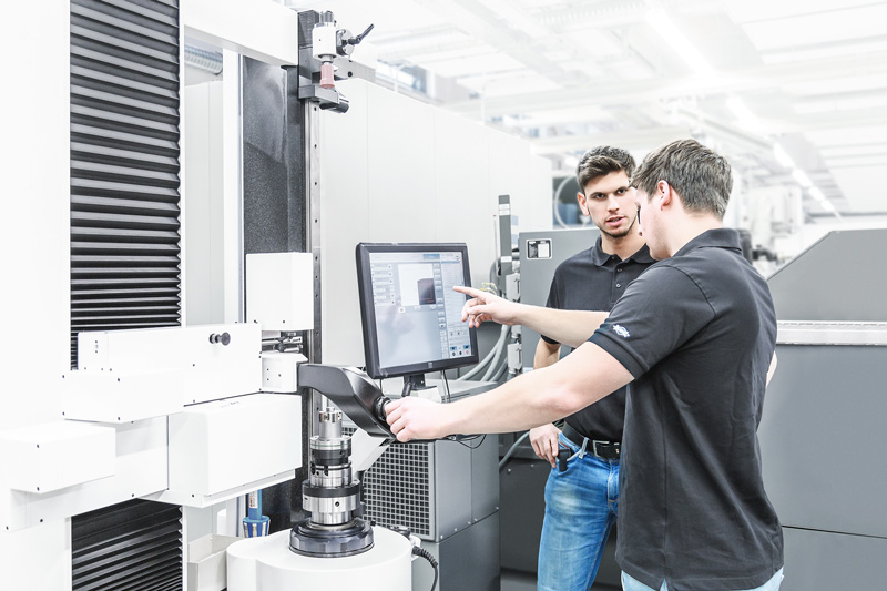Zwei Ingenieure im Gespräch. Sie stehen vor dem Terminal eines Einstellgerätes für Werkzeuge.
