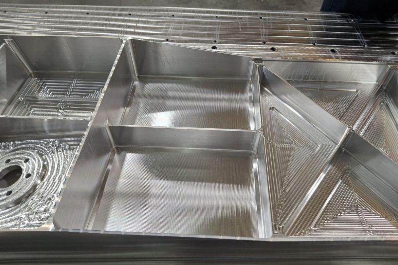 The image shows the aluminium sample component with the milled pockets, which are up to 125 mm deep.